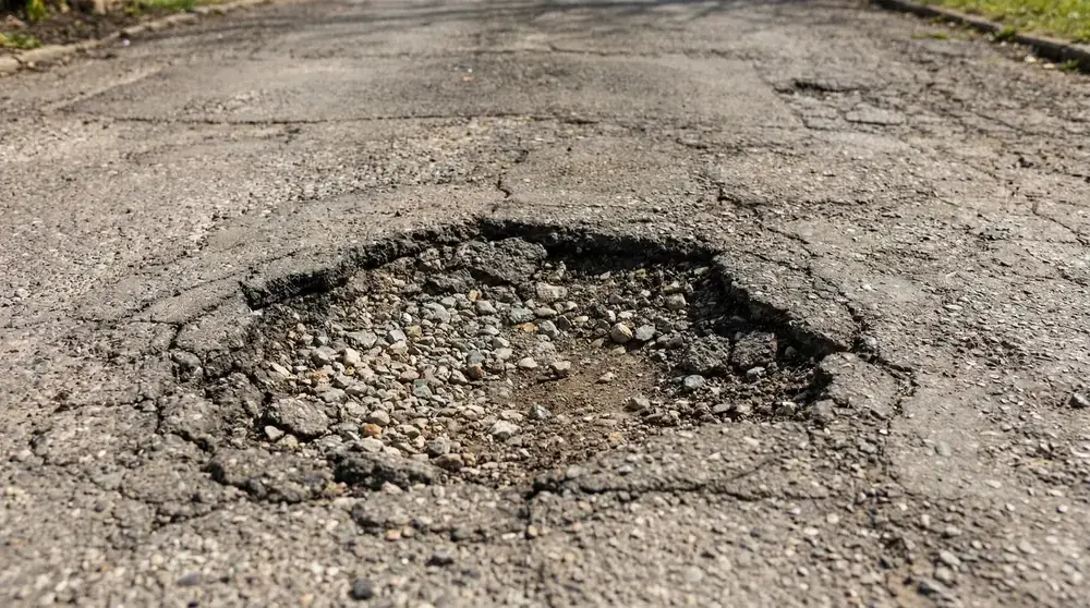Large pothole in asphalt driveway requiring professional repair